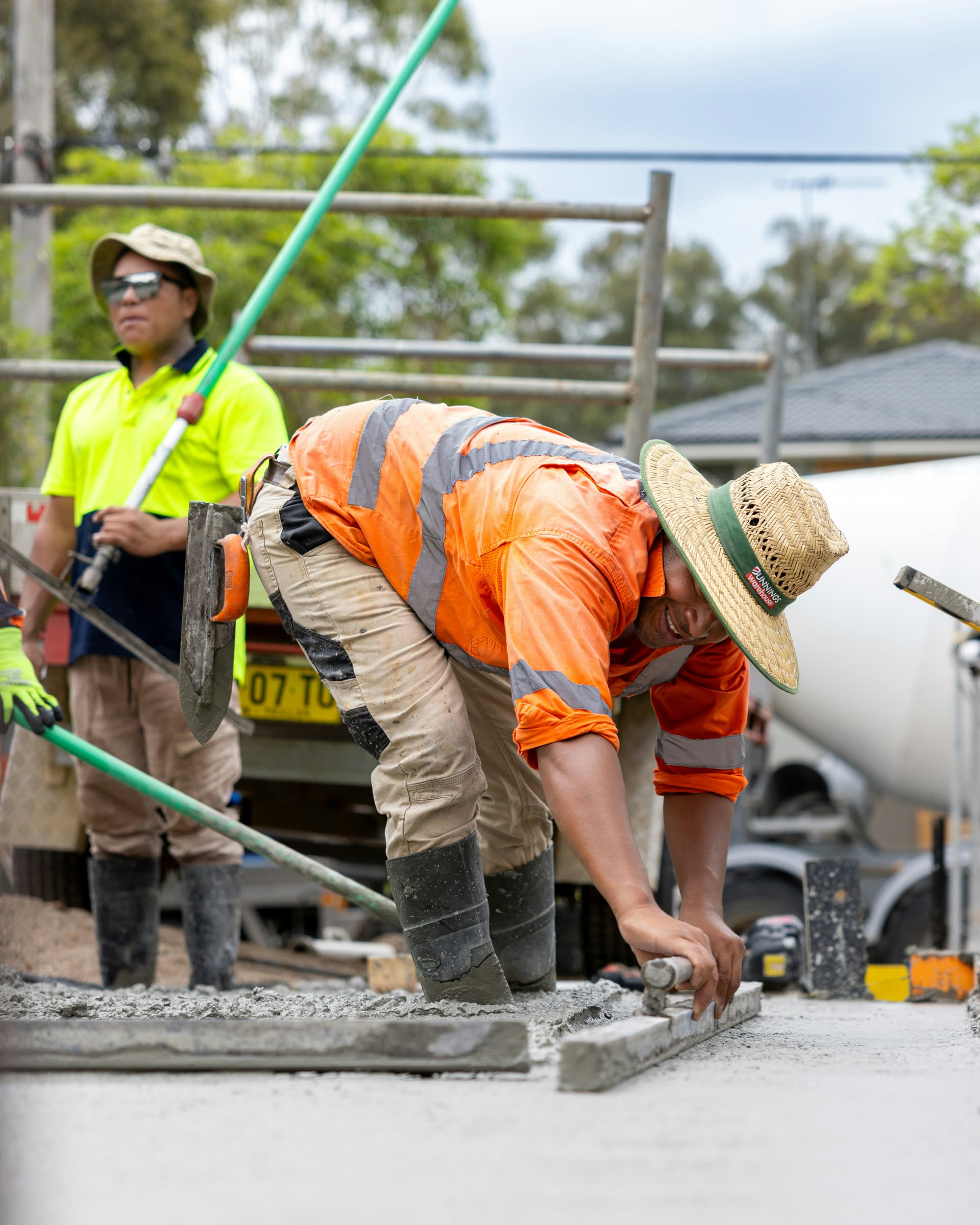 A worker hand-finishing the edge of a fresh concrete slab